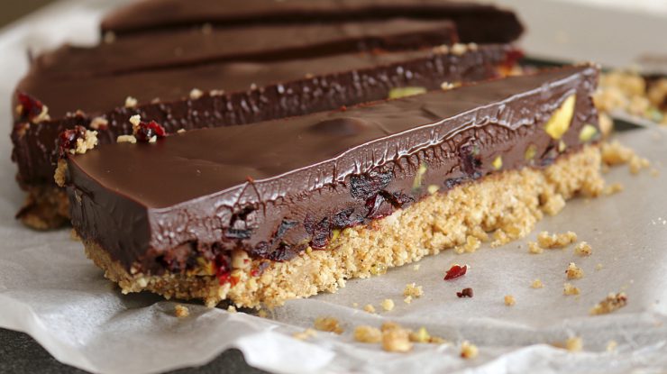 Rich chocolate ganache tart on a biscuit base with cranberries and pistachio nuts